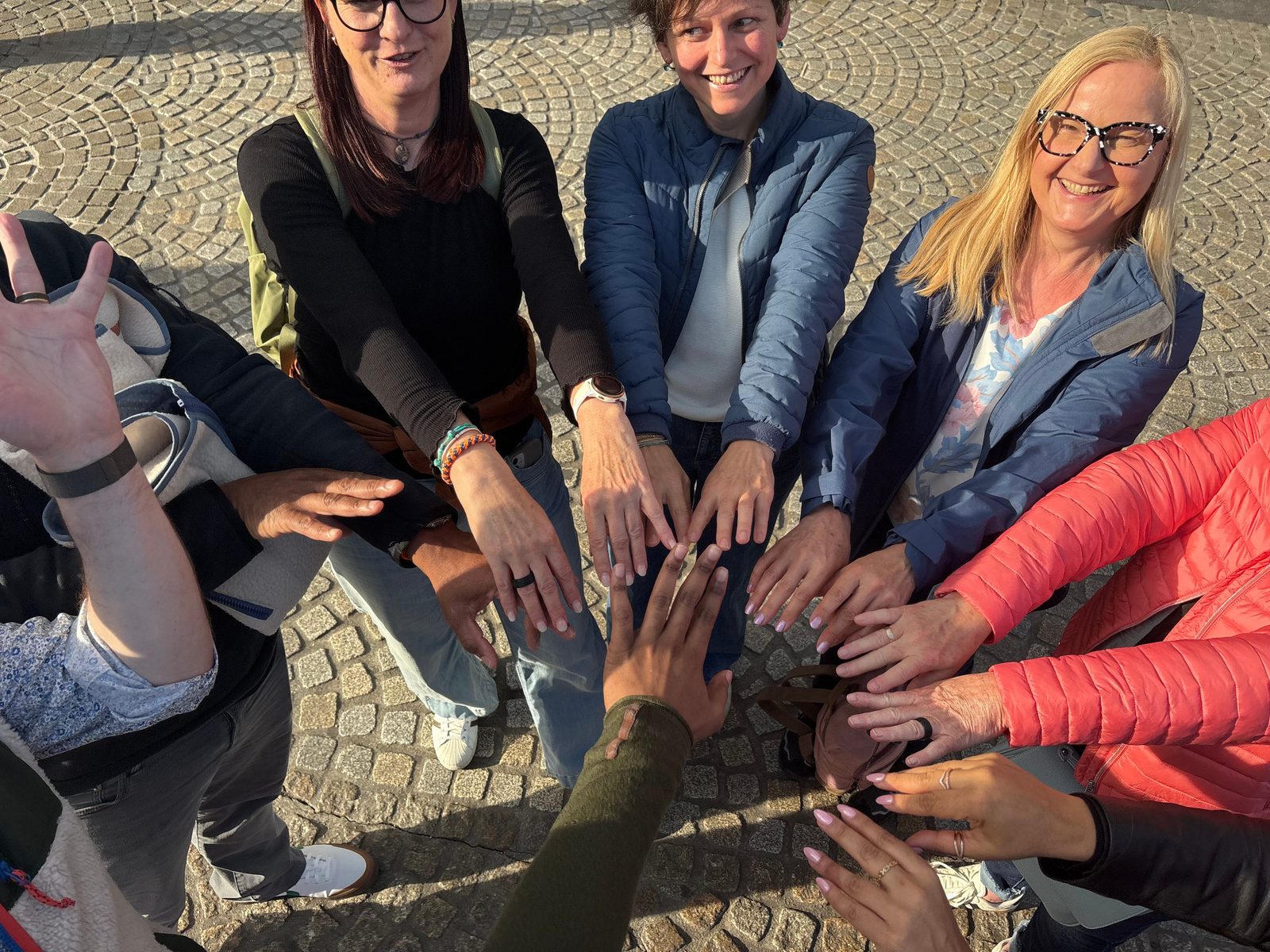 Tour group putting hands together on Amsterdam cobblestones