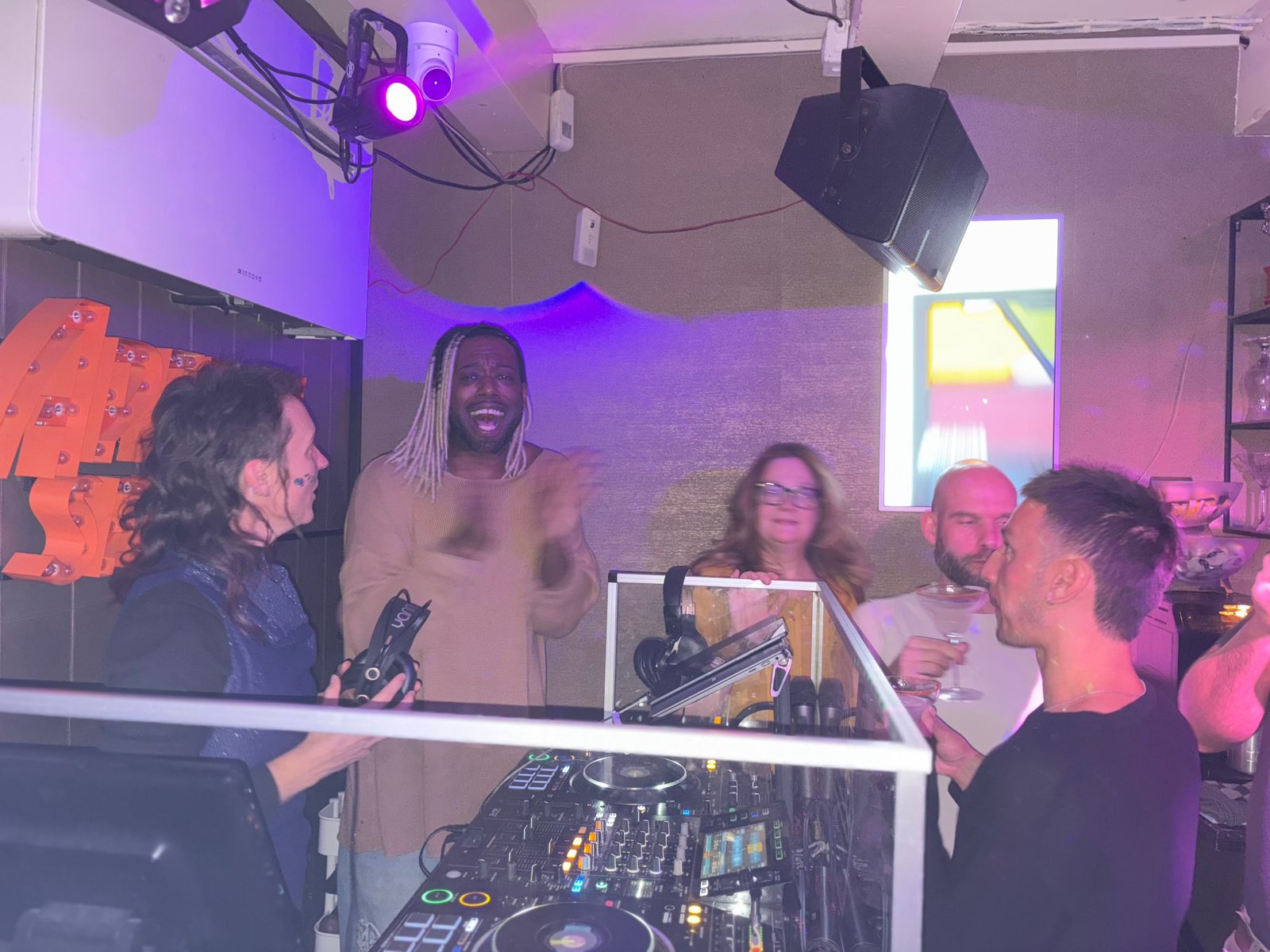 Guests learning to mix behind the DJ decks during an Amsterdam DJ workshop
